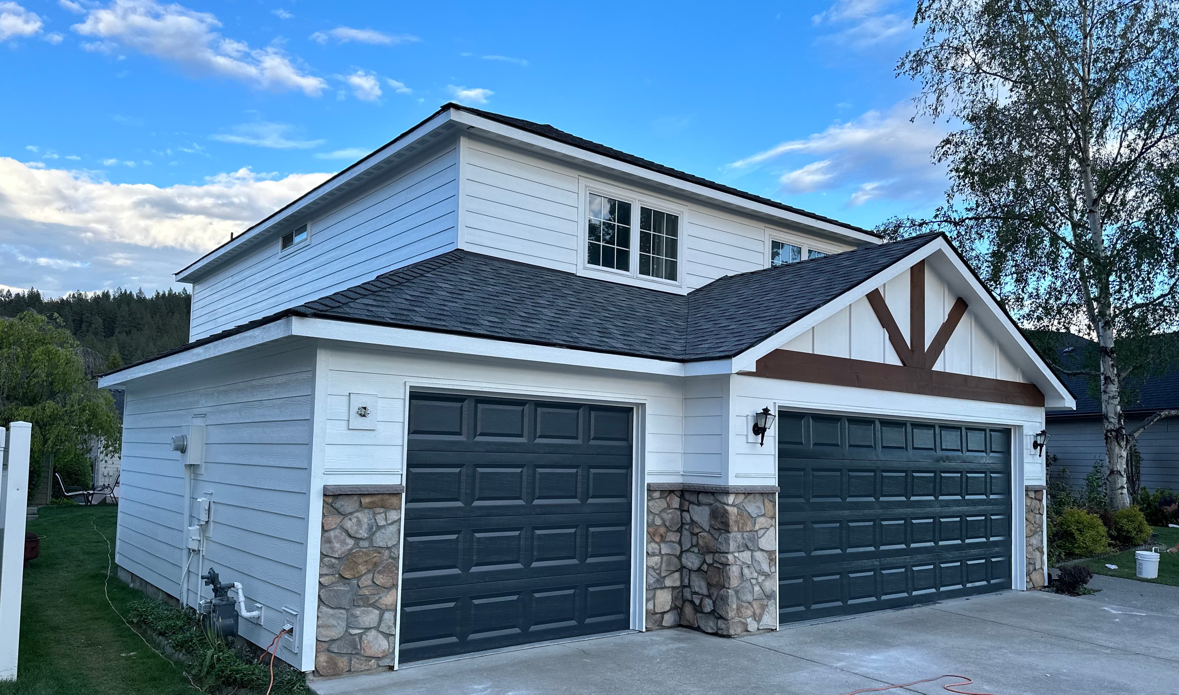 Spokane residence finished by Pro Arkh, white siding with stone veneer and three bay garage